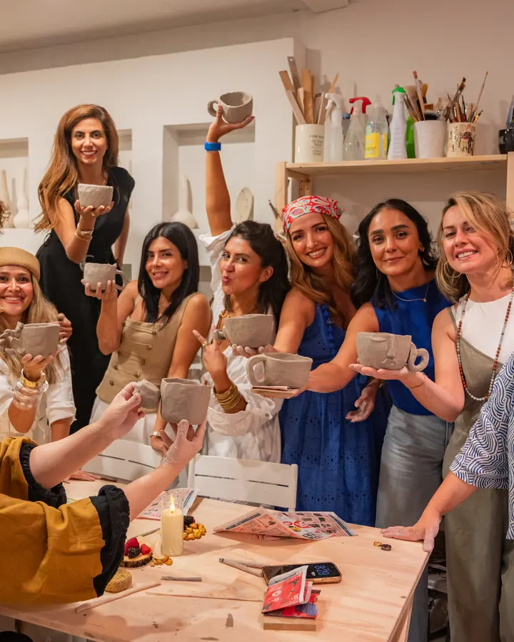 A group of friends cheering with the mugs they made