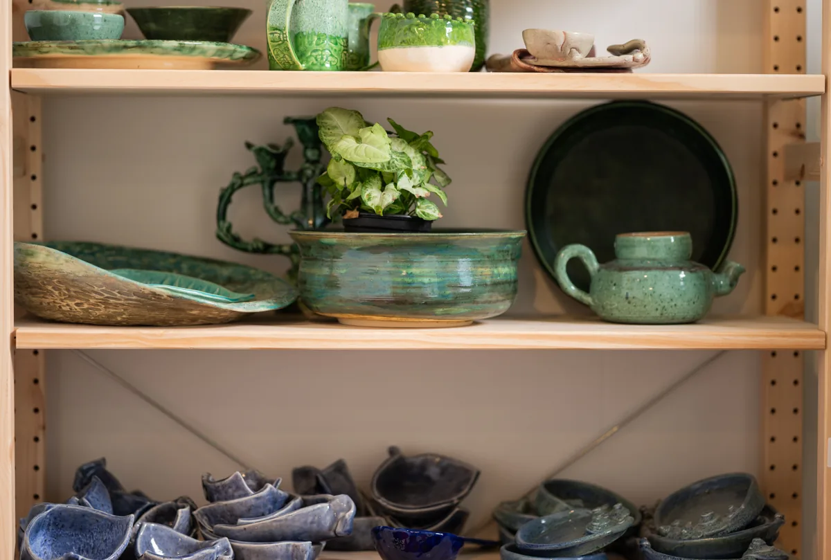 A speckled green teapot, a striped green planter and a row of blue hand-built dishes